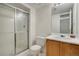 Bathroom with white tiled shower, and a single sink vanity with natural wood cabinet at 2062 S Xenia Way, Denver, CO 80231