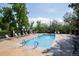 Community outdoor pool surrounded by lounge chairs and mature trees on a sunny day at 10652 W Florida Ave # D, Lakewood, CO 80232