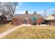 Brick home exterior with an outdoor dining space on a concrete patio with an umbrella and BBQ grill at 1780 Roslyn St, Denver, CO 80220