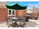 Outdoor patio with dining set, patio umbrella, and a BBQ grill on the brick home exterior at 1780 Roslyn St, Denver, CO 80220