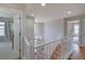 Bright, open hallway featuring hardwood floors, white railing, and a decorative chandelier adding a touch of elegance at 8641 Coors St, Arvada, CO 80005