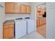 Well-lit laundry room with oak cabinets, washer and dryer, and easy access to the kitchen through a nearby doorway at 8641 Coors St, Arvada, CO 80005