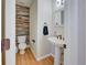 Stylish powder room featuring reclaimed wood accent wall, hardwood floor and pedestal sink at 8641 Coors St, Arvada, CO 80005