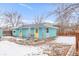 View of the back of a light blue house with a yellow door and a small patio area in the backyard at 457 Verdant Cir, Longmont, CO 80504