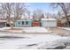 Charming, light blue one-story home with a detached garage and snowy front yard at 457 Verdant Cir, Longmont, CO 80504