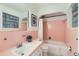 Charming pink tiled bathroom featuring a shower-tub combo, black and white tiled flooring, and plenty of counter space at 845 Everett St, Lakewood, CO 80215