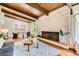 Open-concept living and dining area with a brick fireplace, wood floors, and abundant natural light at 845 Everett St, Lakewood, CO 80215
