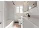 This bright bathroom offers a shower over tub and a white vanity with contemporary fixtures at 1570 S Chase St, Lakewood, CO 80232