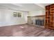 Spacious basement area featuring a brick fireplace, built-in shelving, laminate flooring, and natural light at 11112 Dahlia Way, Thornton, CO 80233