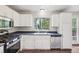 A well-lit kitchen featuring white cabinets, stainless steel appliances, and a window overlooking the backyard at 11112 Dahlia Way, Thornton, CO 80233