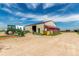 Large barn with open bay, surrounded by gravel and equipment on a sunny day at 46303 E 106Th Ave, Bennett, CO 80102