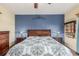 Comfortable bedroom featuring wood floors, a ceiling fan, a blue accent wall, and a patterned comforter at 46303 E 106Th Ave, Bennett, CO 80102