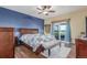 Main bedroom with wood floors, ceiling fan, blue accent wall, and access to a private deck with a view at 46303 E 106Th Ave, Bennett, CO 80102