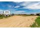 Expansive property with ample parking, outbuildings, and equestrian features under a bright blue, partly cloudy sky at 46303 E 106Th Ave, Bennett, CO 80102