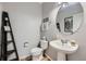 Cozy powder room features pedestal sink, round mirror, and decorative shelving at 11321 Mesa Verde Pl, Parker, CO 80138