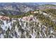 Distant aerial view of a home on a forested hillside with snow covered ground at 13084 Deer Ridge Way, Larkspur, CO 80118