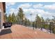 Back deck with wood flooring, iron railing, umbrella, and a wooded view at 13084 Deer Ridge Way, Larkspur, CO 80118