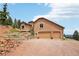 Exterior of a home featuring a three-car garage and terraced landscaping at 13084 Deer Ridge Way, Larkspur, CO 80118