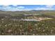 Aerial view of property nestled in a dense forest with a nearby lake and mountain views at 28630 Pine Dr, Evergreen, CO 80439