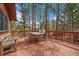 Back deck with table and chair set, as well as a wooden bench, overlooking treed back yard at 28630 Pine Dr, Evergreen, CO 80439