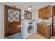 Laundry room includes a white washer and dryer, wood cabinets, window, and decorative wood door at 28630 Pine Dr, Evergreen, CO 80439