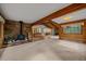 Open living area featuring a stone fireplace, exposed wood beams and a glimpse of the kitchen at 28630 Pine Dr, Evergreen, CO 80439