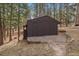 Outbuilding with wood storage and stone pathway to access, surrounded by trees at 28630 Pine Dr, Evergreen, CO 80439