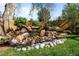 A charming backyard waterfall feature is surrounded by lush landscaping and a wooden fence at 4951 Sanford W Cir, Cherry Hills Village, CO 80113