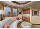 Sitting area with wet bar featuring a curved sofa, glass coffee table, and warm wood trim around the windows at 14154 Lexington Cir, Westminster, CO 80023