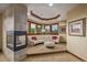 A sitting area with a stone fireplace, tray ceiling, and view of the outdoors through large, trimmed windows at 14154 Lexington Cir, Westminster, CO 80023