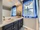 Charming bathroom featuring vanity with blue cabinets and bright blue window treatments at 7296 S Flower St, Littleton, CO 80128
