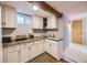 Cozy kitchenette features bright cabinetry, laminate counters, small sink, and light wood floors at 7296 S Flower St, Littleton, CO 80128
