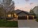 Charming ranch-style home showcasing stone accents, a spacious driveway, and a well-manicured lawn at sunset at 828 Rabbit Run Dr, Golden, CO 80401