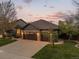Beautifully landscaped home features a stone-accented facade and a spacious driveway at twilight at 828 Rabbit Run Dr, Golden, CO 80401