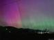 Striking aurora borealis illuminates the night sky over the mountain landscape at 828 Rabbit Run Dr, Golden, CO 80401