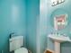 Stylish powder room with a pedestal sink, round mirror, and calming blue walls at 20592 E Lake Ave, Centennial, CO 80016