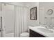 Bright bathroom features white tile, shower curtain, dark wood vanity, and decorative art at 15314 W Baker Ave, Lakewood, CO 80228