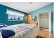 Sunlit bedroom with blue walls, featuring a patterned bedspread and a window view at 5128 S Greenwood Dr, Evergreen, CO 80439