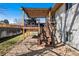 A wooden back deck with an overhead pergola, metal railings, and stairs leading down to a gravel backyard at 7815 Conifer Rd, Denver, CO 80221