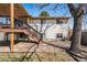 View of the backyard and back of the house with a deck with a pergola and stairs down to a gravel and grass yard at 7815 Conifer Rd, Denver, CO 80221