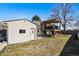 A view of the detached garage and the back of the house with a deck with a pergola, surrounded by grass and gravel at 7815 Conifer Rd, Denver, CO 80221