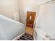 Entryway with staircase featuring neutral walls and black carpeted steps, leading to a warm-toned wood door at 7815 Conifer Rd, Denver, CO 80221