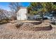 Landscaped yard with a retaining wall featuring a variety of small trees and shrubbery near the home's siding at 7815 Conifer Rd, Denver, CO 80221