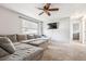 Spacious living room with gray sectional, plush carpet, ceiling fan, and a wall-mounted TV for entertainment at 7815 Conifer Rd, Denver, CO 80221