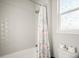 Bright bathroom featuring a shower over tub with floral shower curtain and decorative window at 437 Buckskin Rd, Berthoud, CO 80513
