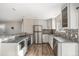 Bright kitchen featuring stainless steel appliances, white cabinetry and a stone backsplash at 6147 Dunraven, Golden, CO 80403