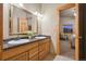 Bathroom featuring double sinks, a granite countertop, a decorative mirror, and natural wood trim at 3842 Estates Cir, Larkspur, CO 80118