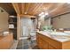 Rustic bathroom with a wood panel ceiling, slate flooring, corner shower, towels, and natural light at 3842 Estates Cir, Larkspur, CO 80118