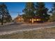 Rustic home with stone and wood accents, surrounded by mature trees and gravel driveway at 3842 Estates Cir, Larkspur, CO 80118