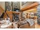 Inviting living room featuring a stone fireplace, wood beam, and comfortable seating at 3842 Estates Cir, Larkspur, CO 80118